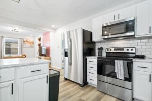 een keuken met witte kasten en een roestvrijstalen koelkast bij Game Room Retreat with Firepit and Gym, Sleeps 12 in Indianapolis +32 foto's