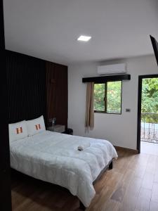 una camera da letto con un grande letto bianco e una finestra di Hotel Sevilla Palenque a Palenque Altre 44 foto