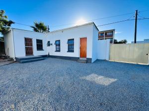 a white building with a fence in a parking lot at Amani in East London