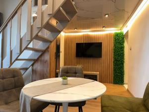 a living room with a table and a tv and stairs at First Line Apartment 2 in Balchik