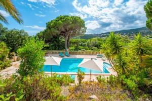 a swimming pool with two umbrellas and trees at Paradis Provençal in Sainte-Maxime