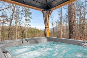 a jacuzzi tub with a view of the woods at Grassy Paradise by Avada Properties in Sevierville