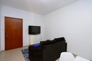 ein Wohnzimmer mit einem schwarzen Stuhl und einem TV in der Unterkunft A 900 m da Redenção wi-fi 170 Mbps estilo e conforto na Cidade Baixa in Porto Alegre