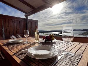 a wooden table with a plate of food and wine glasses at Sea Cottage overlooking Seagull Island in Porto Rafael