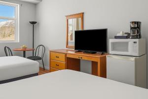 a bedroom with a bed and a television on a desk at Comfy Rockies Retreat for 4 Canmore DT Near Banff in Canmore