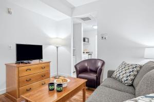 a living room with a couch and a tv and a table at Serene 1BR Retreat Mtn Views, Pool, and Hot Tub in Canmore
