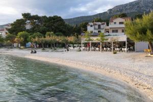 ein Strand mit einer Gruppe von Gebäuden und dem Wasser in der Unterkunft Vela Mala in Kaštela