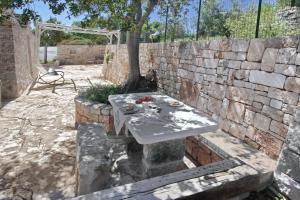 a stone wall with a table in front of a tree at Trullo San Giovanni in Castellana Grotte
