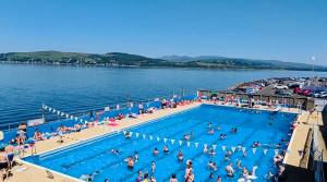 a group of people in a swimming pool in the water at THE RESTING LION - Gourock Town Center Holiday Home Apartment in Gourock