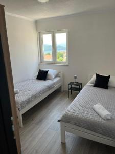 two beds in a room with two windows at Apartman Ante in Neum