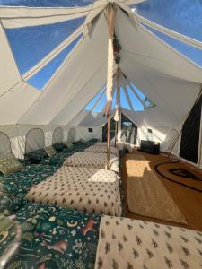 a marquee with a row of beds in a tent at GreenFeilds Glamping Stargazing Yurts and Outdoor Spa in Milwich +20 photos