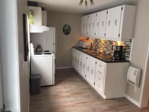 a kitchen with white cabinets and a white refrigerator at Maison d'Imelda in Petit-Saguenay