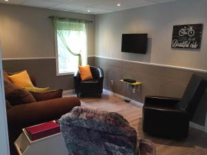 a living room with a couch and chairs and a tv at Maison d'Imelda in Petit-Saguenay