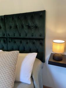 a bed with a green padded headboard and a lamp at Casa Pepina in Pedroso