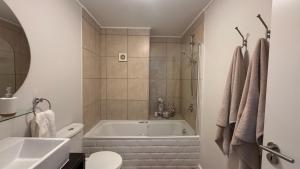 a bathroom with a tub and a toilet and a sink at Beachview Apartment in Hout Bay +36 photos