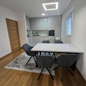 ポドゴリツァにあるViolet- City Kvart Luxury 2 Bedroomの白いテーブルと椅子のあるダイニングルーム +4枚の写真