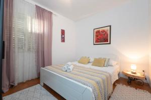 una camera da letto bianca con un letto e una finestra di Apartment Renko a Omiš (Almissa)
