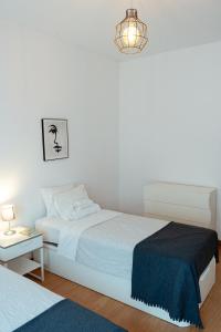 Dormitorio blanco con cama y lámpara en StayinSetubal, en Setúbal