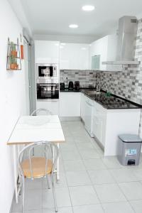 Una cocina con gabinetes blancos y una mesa y sillas. en StayinSetubal, en Setúbal 12 fotos más