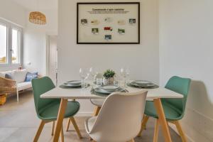 a dining room with a white table and green chairs at Mike&Jo Cozy apartments-Near FCO airport, in Ostia Antica in Ostia Antica