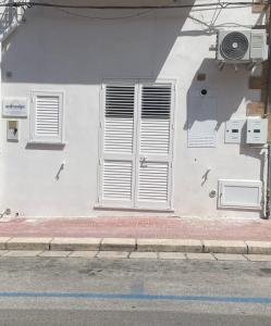 a white building with white shutters on the side of a street at Anfrasipe apartment in Terrasini