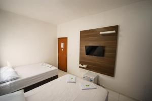 ein Hotelzimmer mit zwei Betten und einem Flachbildfernseher in der Unterkunft Hotel Janaína in Porto Belo