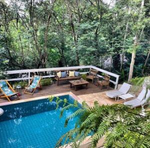 a backyard with a swimming pool and a wooden deck at BOSQUE TOQUE TOQUE Pousada in São Sebastião