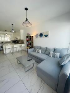 a living room with a blue couch and a table at Sea Breeze - Oroklini in Voroklini