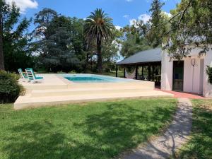a swimming pool with two blue chairs next to a house at Villa María, nature and relaxation in Gualeguay