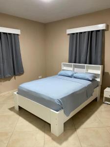 a white bed with blue pillows in a bedroom at Residence Mont Vernon II - B in Cul de Sac