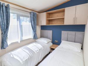 twee bedden in een kleine kamer met een raam bij Maple Lodge in Whitby