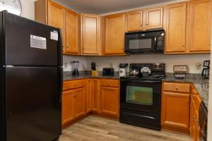 a kitchen with black appliances and wooden cabinets at Cozy Vista Condo by Avada Properties in Pigeon Forge