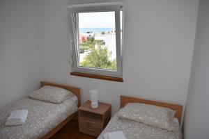 two beds in a room with a window at Apartman KiP in Zadar