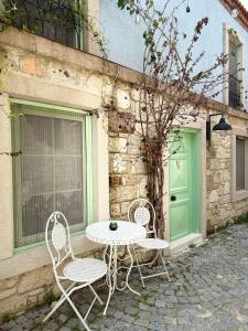 Zwei Stühle und ein Tisch vor einem Gebäude mit einer grünen Tür in der Unterkunft Sadele Hacımemiş in Cesme