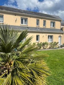 a large building with a palm tree in front of it at Gites de la Mouette Le Bigorneau nid cotier 2 personnes in Ravenoville