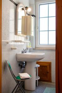 a bathroom with a sink and a chair next to it at Manzoni Apartment in Le Castella
