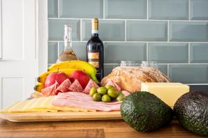 a cutting board with meat and fruit and a bottle of wine at KGV Stays - Sant Bank City Apartment, 1 bed, modern, central, near beach in Bournemouth