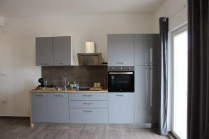 une cuisine avec des armoires blanches, un évier et un micro-ondes dans l'établissement Apartman Lavanda, à Šibenik