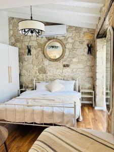 ein Schlafzimmer mit einem weißen Bett und einer Steinwand in der Unterkunft Sadele Hacımemiş in Cesme