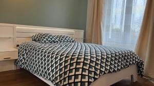 a bed with a black and white comforter and a window at Appartement Quartier Jardin Public in Parthenay