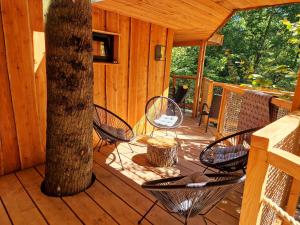 a wooden porch with chairs and a tree at Les Cabanes du Beau Vallon in Profondeville