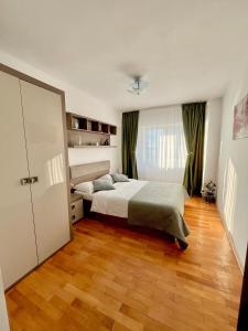 a bedroom with a bed and a wooden floor at Valcea Northside Spacious Apartment in Râmnicu Vâlcea