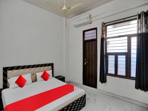 Un dormitorio con una cama con almohadas rojas y una ventana. en Hotel O Hotel Valentine's, en Rohtak
