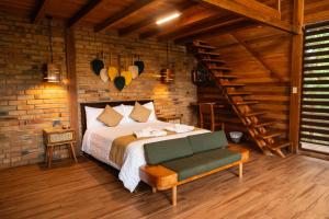 a bedroom with a bed and a brick wall at Cabaña "Los Cedros", Sumak Cabañas in Baeza