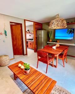 a living room with a wooden table and a kitchen at Patacho Brisa Mar - Triplex na Rota Ecológica dos Milagres in Pôrto de Pedras