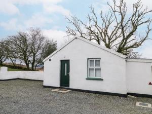a white house with a green door and trees at Ballard Cottage Annexe in Newry