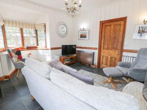 a living room with a couch and chairs and a tv at Bwthyn y Coediwr The Woodcutters Cottage in Blaenau-Ffestiniog