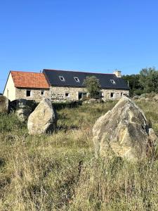 ein Haus auf einem Feld mit Felsen davor in der Unterkunft Menhirs et Moutons Ouessant in Plouëc