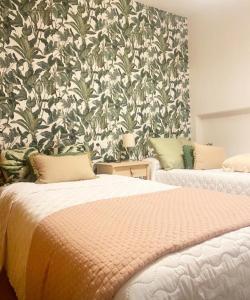 a bedroom with two beds and a floral wallpaper at Lula Apartamento in Betanzos