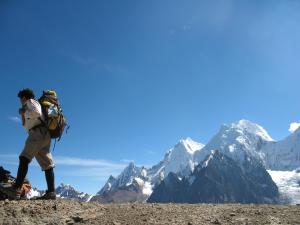 a man with a backpack standing on top of a mountain at Huayhuash Trek - Cuartelhuain Huayllapa 6 days in Huaraz